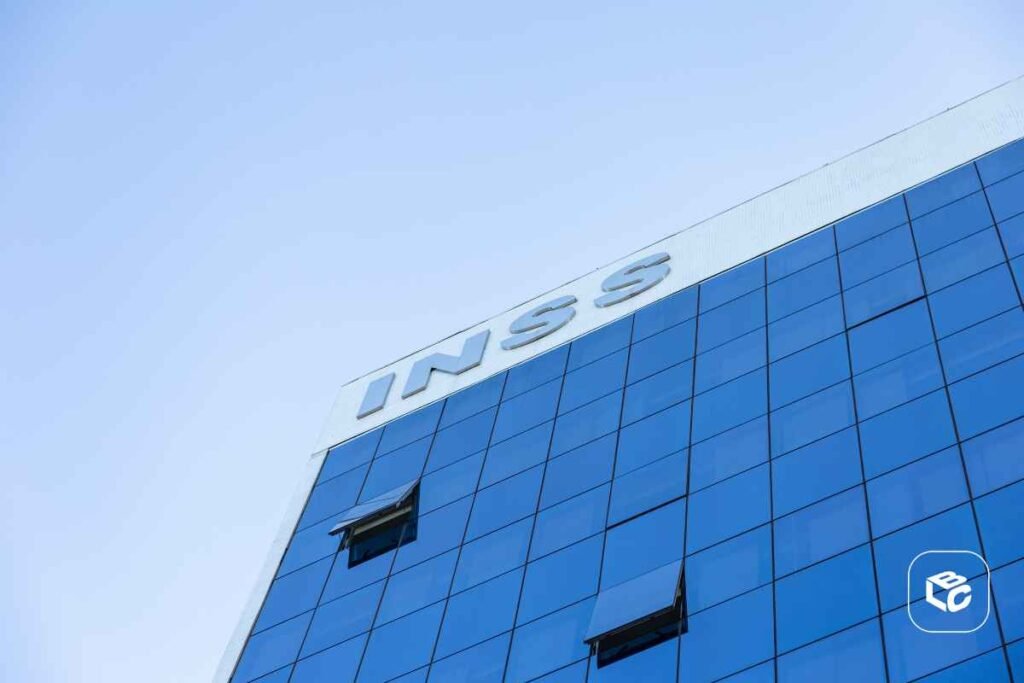 Fachada moderna de agência do INSS com revestimento em vidro espelhado azul, ilustrando previdência social, aposentadoria, benefícios e serviços públicos no Brasil.